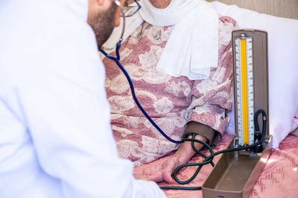 Lääkäri tarkistaa vanhan naisen verenpaineen ja sykkeen pulssit - Valokuva, kuva