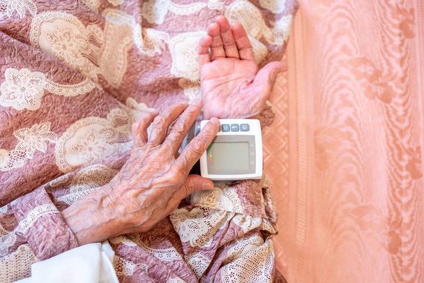 Arabic old woman check her blood pressure using electronic pressure device - Foto, Imagem