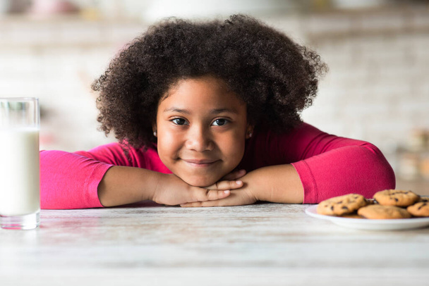 Curly African-American girl preferring cookies instead of milk for breakfast - Photo, image