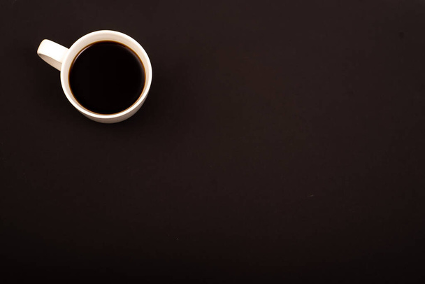 Top view of white ceramic mug with black coffee on black background. Copy space - Foto, Bild