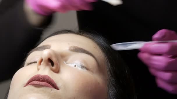 Modern szempilla gyógyító laminálás eljárás egy professzionális szépségszalonban. A szempilla curling eljárás előtt a mester speciális tisztítóhabot alkalmaz a szemen. - Felvétel, videó