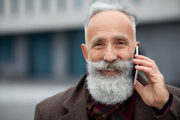 Nahaufnahme eines gut gelaunten alten Mannes, der am Telefon spricht - Foto, Bild