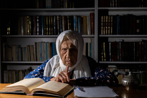Una anciana escribiendo y leyendo un libro a la luz de la mañana - Foto, Imagen