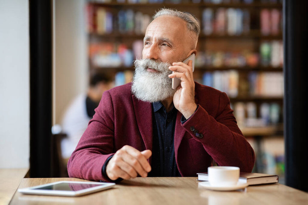 Πολυάσχολος ηλικιωμένος επιχειρηματίας μιλάει στο τηλέφωνο στο καφέ - Φωτογραφία, εικόνα