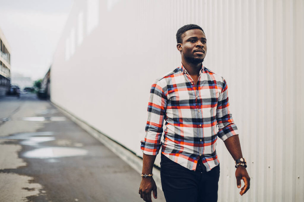 Portret van een gelukkige zwarte man in een geruit shirt lopend in de stad - Foto, afbeelding