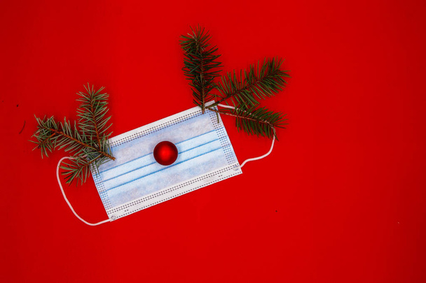 ιατρική μάσκα με χριστουγεννιάτικο δέντρο με τη μορφή ελαφιού σε κόκκινο φόντο - Φωτογραφία, εικόνα