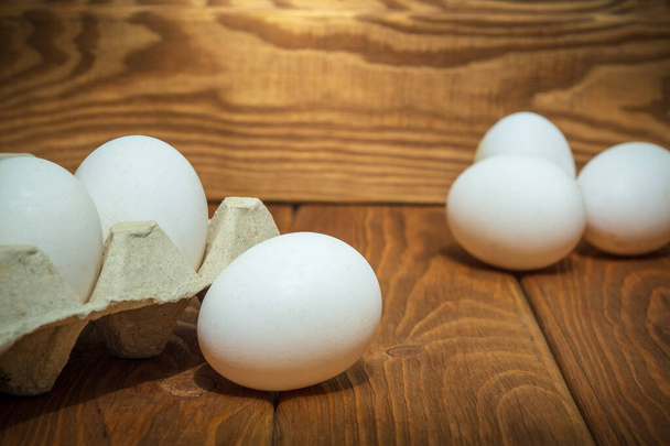 Le uova bianche sono impilate in un vassoio e su tavole vintage. Selezione uova in allevamento di polli - Foto, immagini