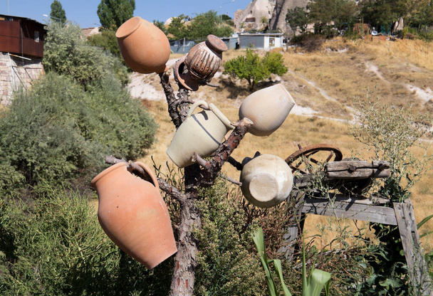 カッパドキアの願い事木、トルコ、乾燥した木の枝にある粘土のジャグと背景にある熱気球を飛んでいます - 写真・画像