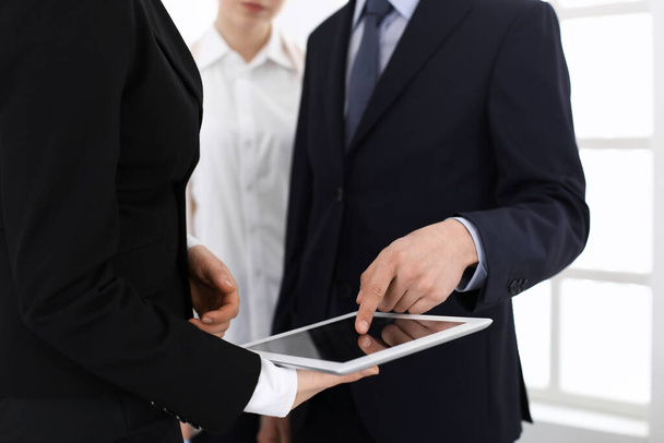Businessman and woman using tablet computer for discussing questions in office. Partners or colleagues at meeting. Business cooperation concept - Photo, Image