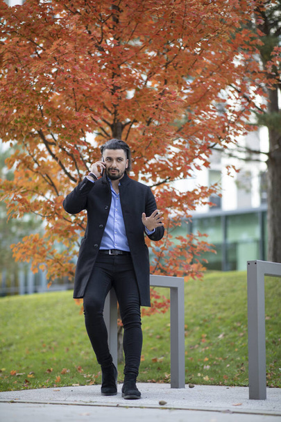 Handsome young man talking on the phone outside autumn - Foto, imagen