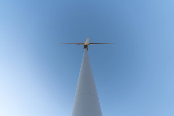 Windkraftanlage im Süden Spaniens, das Windrad ist weiß, hat drei Propeller, der Himmel ist klar - Foto, Bild