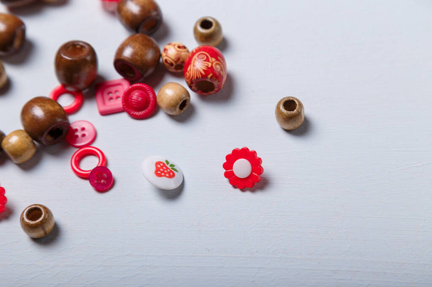 Close-up shot van kralen en knopen voor naaien en borduren. Bruine en rode set van materialen voor handwerk, maken van bijouterie en accessoires. Kopieerruimte. - Foto, afbeelding