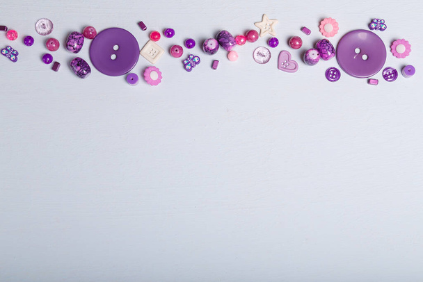 Gros plan des perles et des boutons pour la couture et la broderie. Ensemble violet de matériaux pour l'artisanat, la fabrication de bijouterie et d'accessoires. Fond blanc, espace de copie. - Photo, image