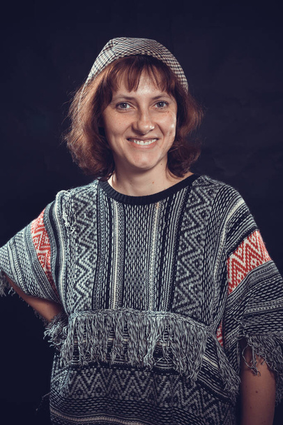 Cheerful 40 years old woman dressed in jeans and poncho studio portrait - Zdjęcie, obraz