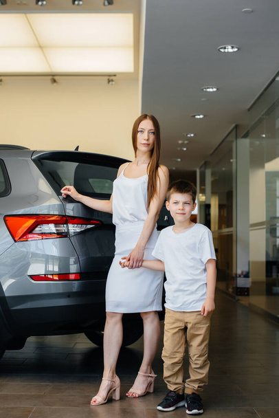 A happy mother with her young son chooses a new car at a car dealership. Buying a car - Photo, Image