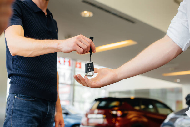 The seller passes the keys to a new car to a young family. Buying a new car - Photo, image