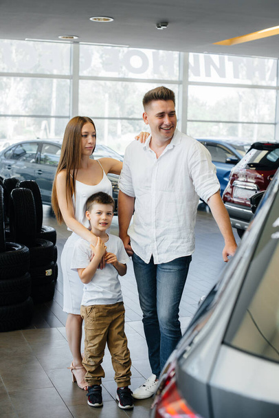 A happy young family chooses and buys a new car at a car dealership. Buying a new car - Fotó, kép