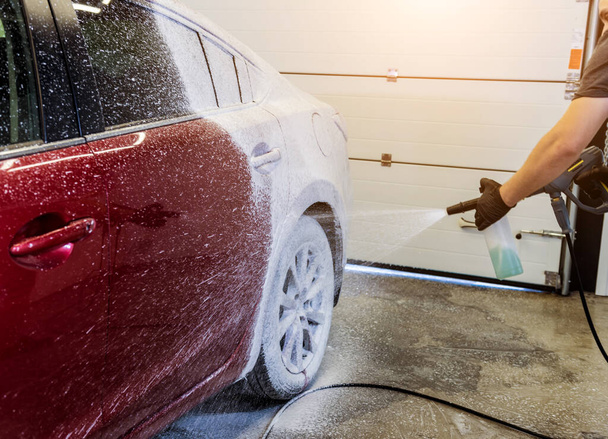 Worker washing car with active foam on a car wash. - Photo, Image