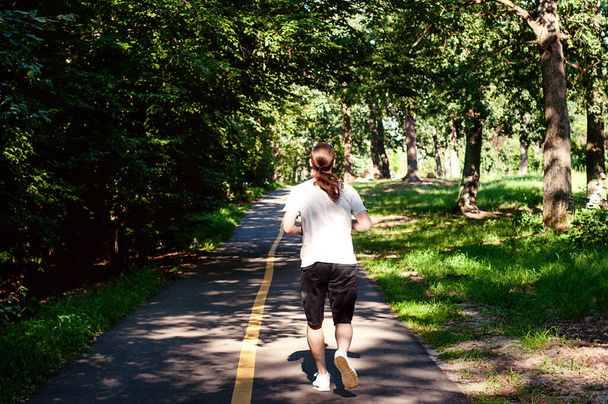 Młody człowiek biegnie po drodze - zachód słońca oświetlony - Zdjęcie, obraz