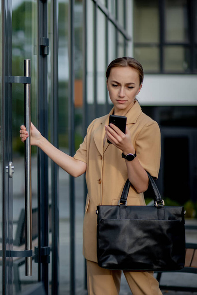 Professional business woman using mobile phone outdoors. Female texting on smart phone while walking outdoor in city - Foto, Bild