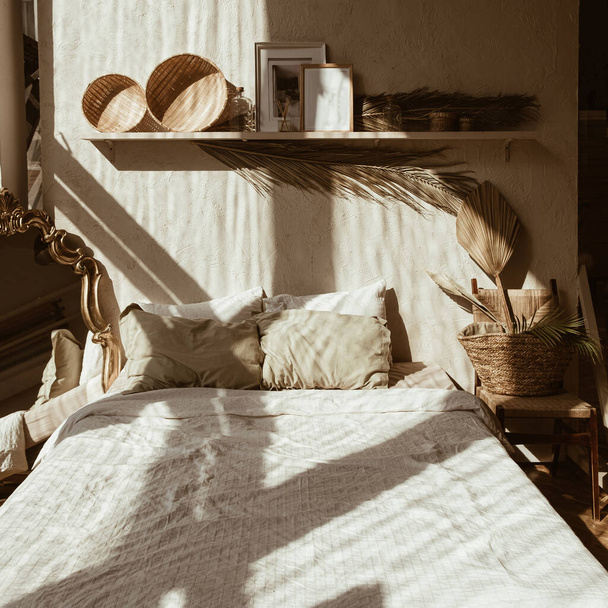 Moderni boho tyyli kodin sisustus. Boheemi makuuhuone. Lämpimät auringonvalon varjot seinällä. Hyggen konsepti. - Valokuva, kuva