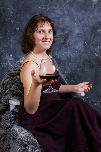 Cheerful 40 years old woman in classic dress with glass of wine - Zdjęcie, obraz