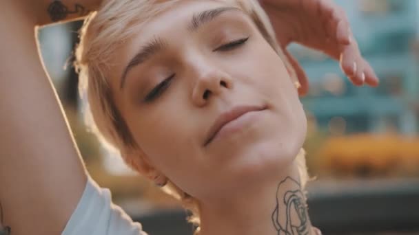 Portrait of beautiful young short haired blond woman in the park during the sunset - Footage, Video