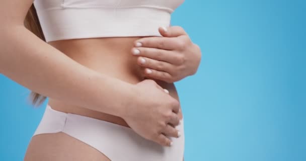 Боль во время менструаций. Крупный план молодых неузнаваемых женщин, трогающих ее желудок, чувствующих боль и судороги - Кадры, видео
