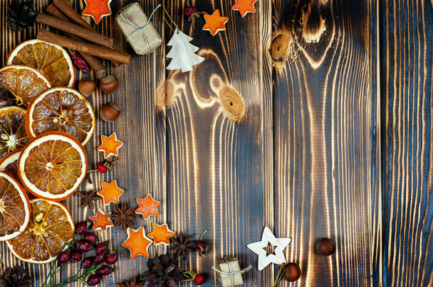 Winterkomposition mit Tannenzapfen, Gewürzen, Scheiben getrockneter Zitrusfrüchte und Walnüssen auf einem alten bemalten Holzgrund. Ansicht von oben - Foto, Bild