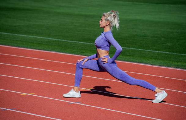 sexy sporty lady stretching and warming up in sportswear on stadium running track, health care - 写真・画像