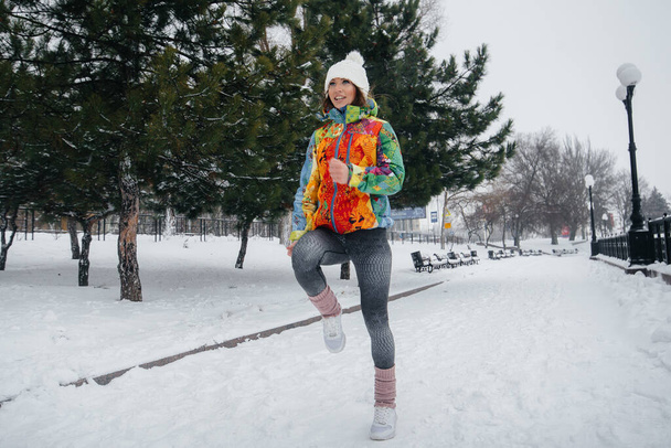 A beautiful young girl is Jogging on a frosty and snowy day. Sports, healthy lifestyle - Foto, Imagen
