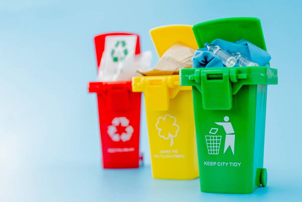 Yellow, green and red recycle bins with recycle symbol on blue background. Keep city tidy, Leaves the recycling symbol. Nature protection concept. - Foto, imagen