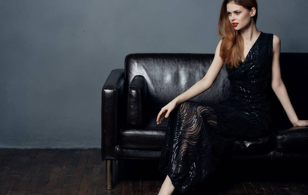 Pretty woman in black dress sits on luxury couch red lips - Фото, зображення