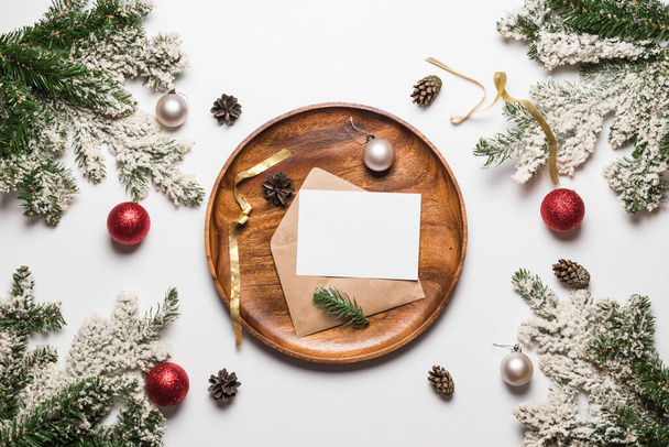 Weihnachts- und Neujahrseinladung im Umschlag auf Holzschale mit Weihnachtsdekoration. Flach lag das Winterferienkonzept. Festkarte - Foto, Bild