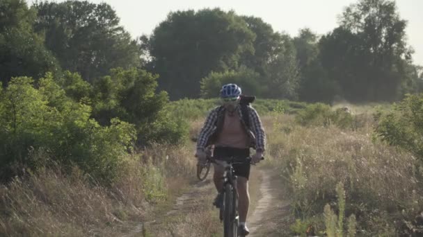 Kırsalda bisiklete binen mutlu çift. Fitness, spor, insanlar ve sağlıklı yaşam tarzı konsepti. Kırsal kesimde tatil bisikleti. Aktif çift bisikletçiler manzaralı yolda dağ bisikleti sürerler - Video, Çekim