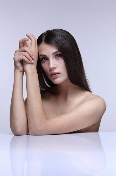 Studio beauty portrait of a brunette girl with bare shoulders on a light background - Photo, Image