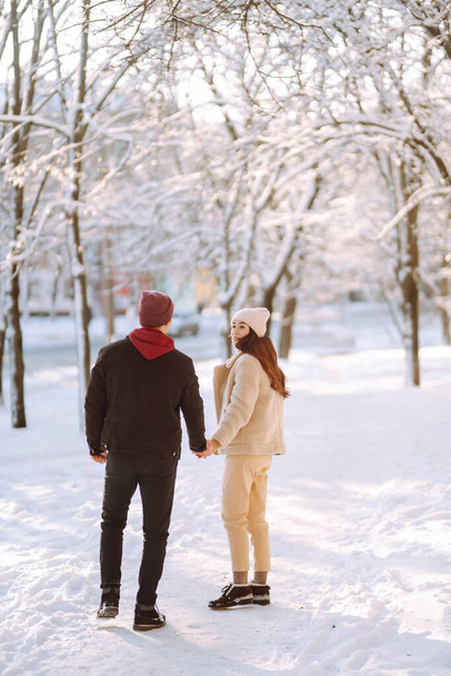 Młoda para na zimowych wakacjach w zaśnieżonym lesie. Szczęśliwy mężczyzna i kobieta bawią się i śmieją na świeżym powietrzu w zimie. Ludzie, sezon, podróże, miłość i rekreacja. - Zdjęcie, obraz