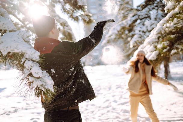 Young couple on winter holiday in a snowy forest. Happy man and woman having fun and laughing outdoors in winter. People, season, travel, love and leisure concept. - Photo, image