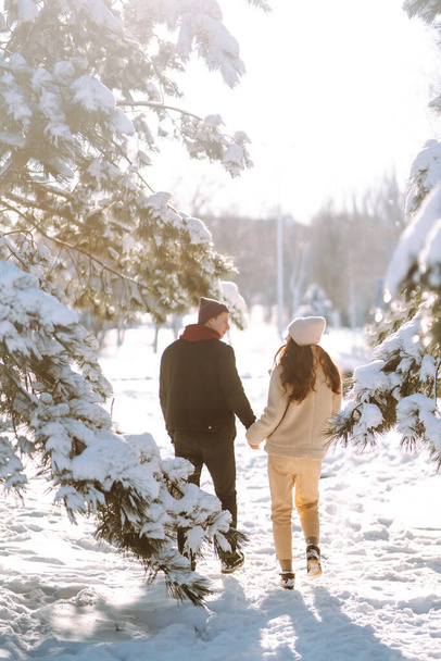 Genç çift kış tatilinde karlı bir ormanda. Mutlu erkek ve kadın kışın dışarıda eğleniyor ve gülüyorlar. İnsanlar, mevsim, seyahat, aşk ve eğlence konsepti. - Fotoğraf, Görsel