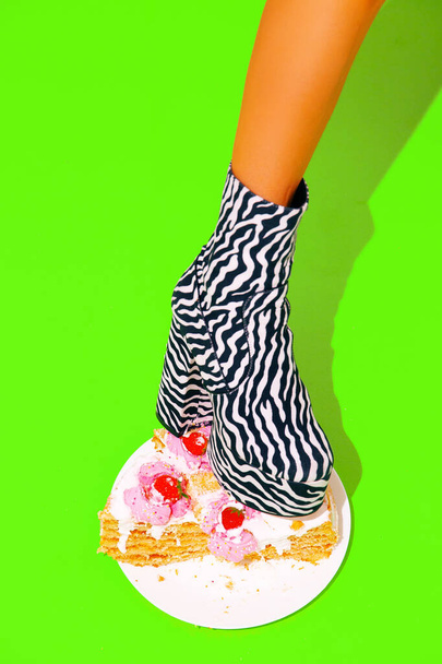 Leg in zebra Party Boots crush yummy cake. Minimal fashion food art - Photo, Image