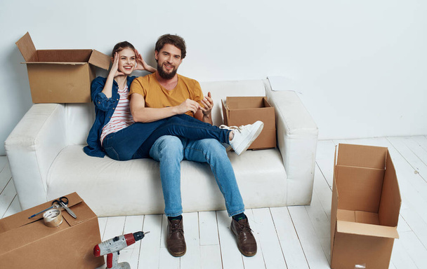 Muž a žena doma na bílém gauči pohybující se kolaudační boxy - Fotografie, Obrázek