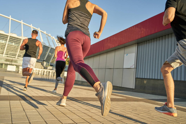 Giovani sportivi che corrono lungo la strada asfaltata - Foto, immagini