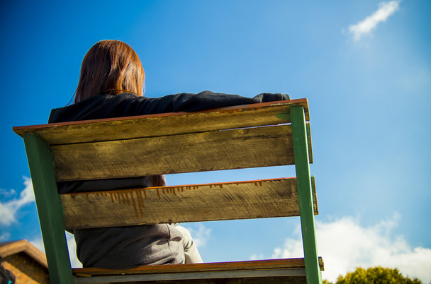 achterkant van vrouw zitten op houten stoel met blauwe sky2 - Foto, afbeelding