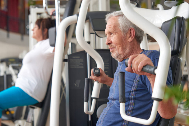 Yaşlı adam spor salonunda güç egzersizi yapıyor.. - Fotoğraf, Görsel