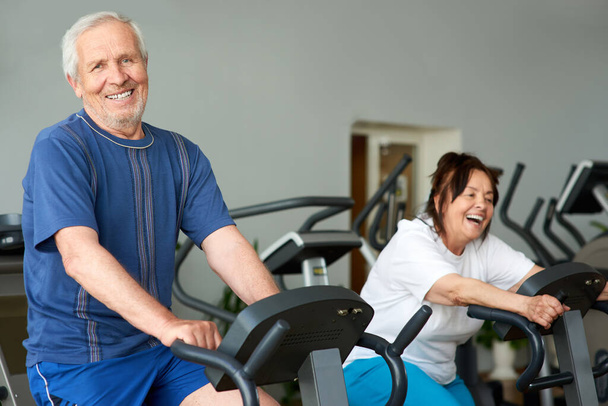 Elderly man working out on exercise bike in gym. - Photo, Image