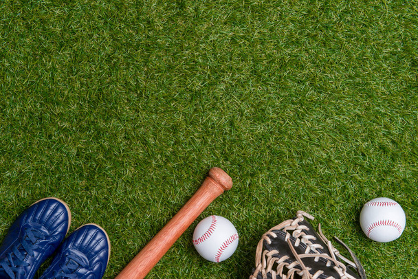 Honkbalknuppel, schoenen, handschoen en bal op groen grasveld. Sport thema achtergrond met kopieerruimte voor tekst en reclame - Foto, afbeelding