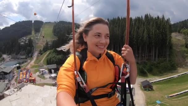 Tourist girl is riding or sliding zipline or trolley over nature from mountain - Footage, Video
