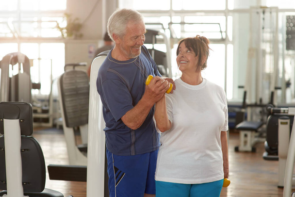 Glückliches Senioren-Paar trainiert gemeinsam im Fitnessstudio. - Foto, Bild