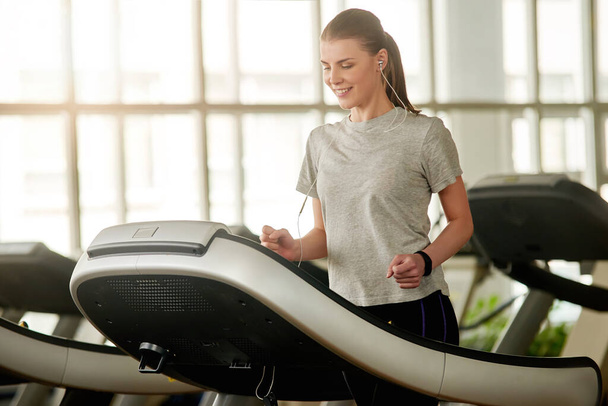Young woman doing cardio exercise on treadmill in gym. - Photo, Image