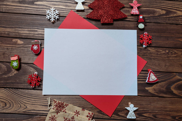 Karácsonyi üdvözlőlap. fehér üres lap egy fa asztalon díszített karácsonyi játékok és szimbólumok. Angyalok, hópelyhek, ajándéktáska. levél a Télapónak. - Fotó, kép